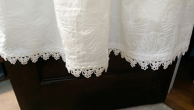 Hem of a dress with scalloped lace edging.
